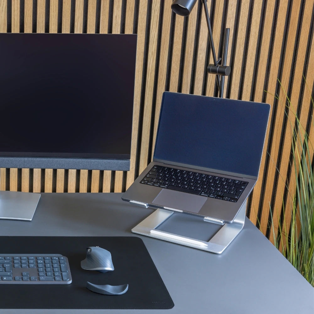 Moderner Arbeitsplatz mit silbernem Laptop-Ständer (NOTEUP), Laptop, schwarzer Tastatur, ergonomischer Maus und Handauflage. Hintergrund aus Holzlamellen, schlichter Stil mit optimaler Ergonomie.
